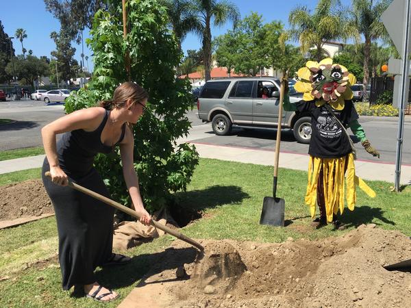 Photo showing woman digging and person in costume